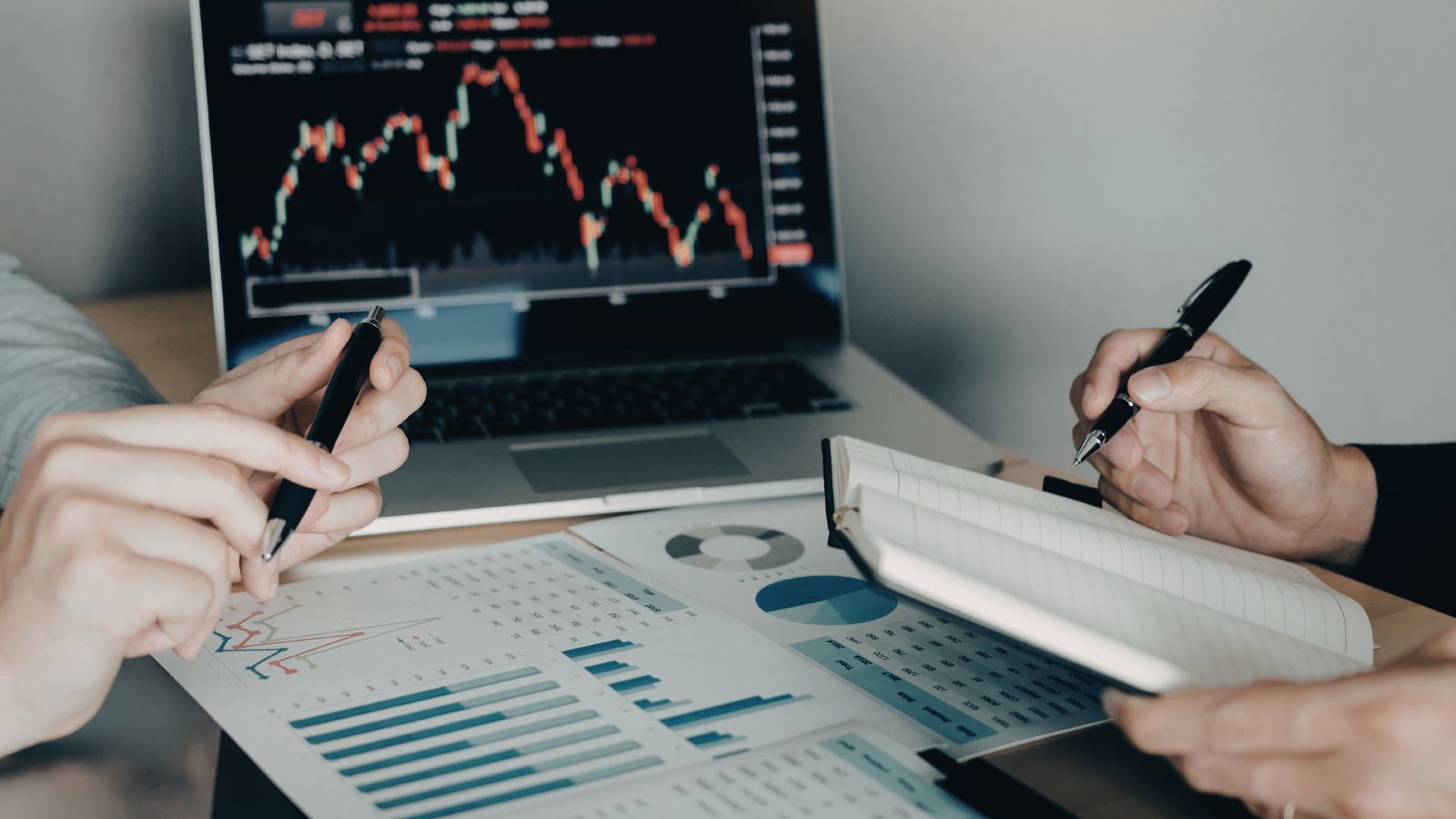 Investors comparing market charts on a laptop and printed reports — Dubai property investor insights from Mitchell's Commercial Real Estate